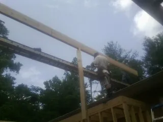 Carpenter setting a ridge beam over a new addition frame — Ice Dam Removal by Roofing Brothers in Pepperell