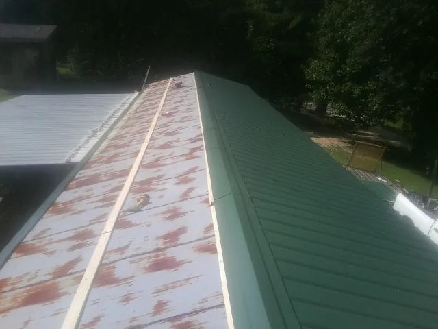 Old rusted panels beside newly installed green metal roofing — Wind Damage Roof Repair by Roofing Brothers in Pepperell
