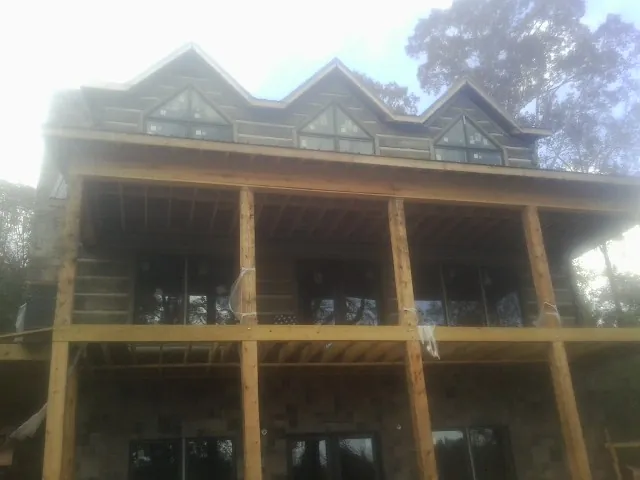 Dormers and porch framing on a large log home under construction — Roof Coating work by our crew in Pepperell