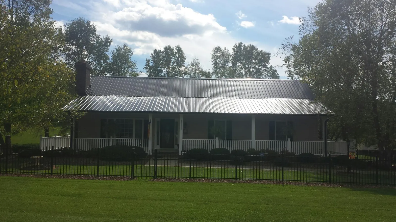 Gray metal roof on a brick ranch with a full width front porch — Gutter Guard Installation work by our crew in Pepperell