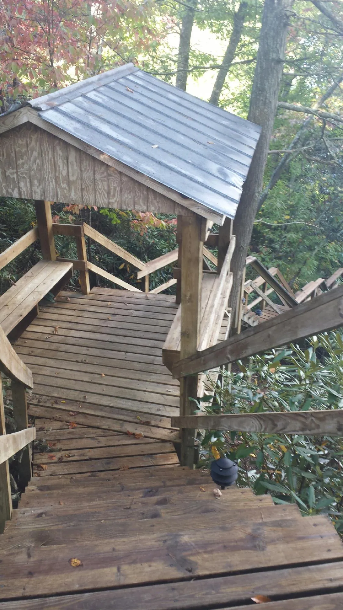 Metal roofed shelter over wooden steps on a wooded walkway — Skylight Repair & Installation work by our crew in Pepperell