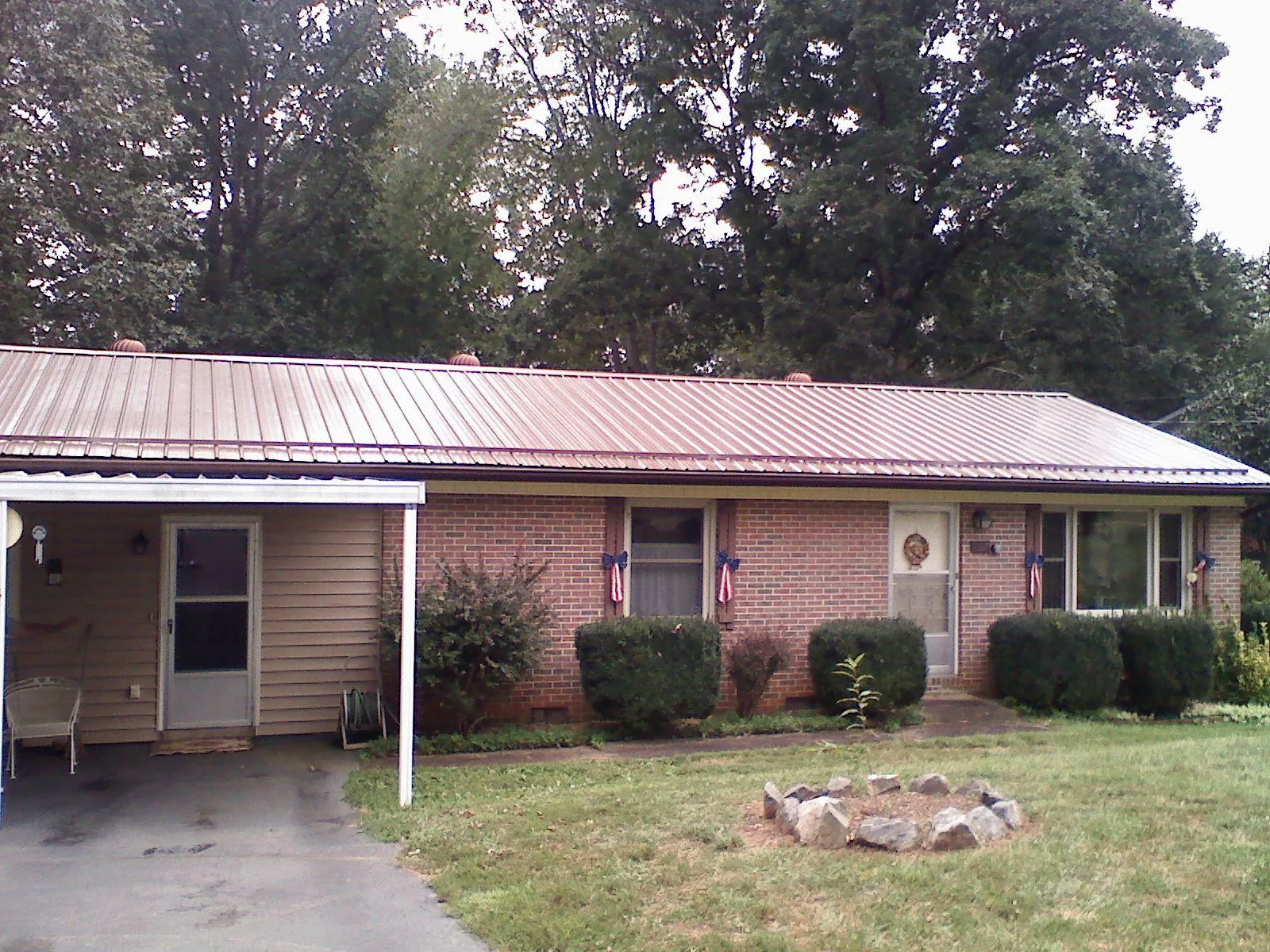 Bronze metal roof and carport on a brick ranch home — Roof Repair work by our crew in Pepperell
