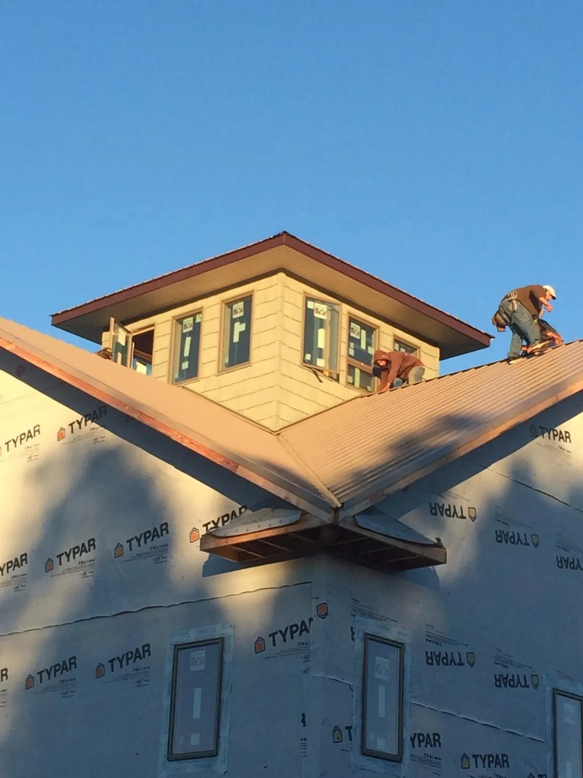 Roofers working around a rooftop cupola on a new metal roof at sunset — Roof Waterproofing in Pepperell by Roofing Brothers